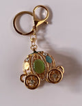 Portachiavi gioiello tridimensionale a forma di carrozza di Cenerentola in metallo dorato traforato con strass brillanti e pietre ovali levigate nei colori verde, azzurro e madreperla, con ganci dorati.