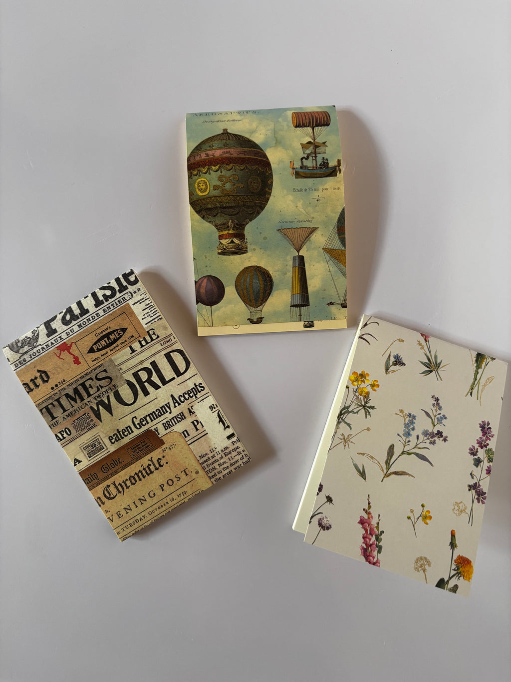 Selezione di tre blocchetti memo d'autore selezionati da C.Moon  con tre diverse grafiche di copertina vintage: quotidiano d'epoca, mongolfiere vintage e motivi di erbario botanico con fiori.