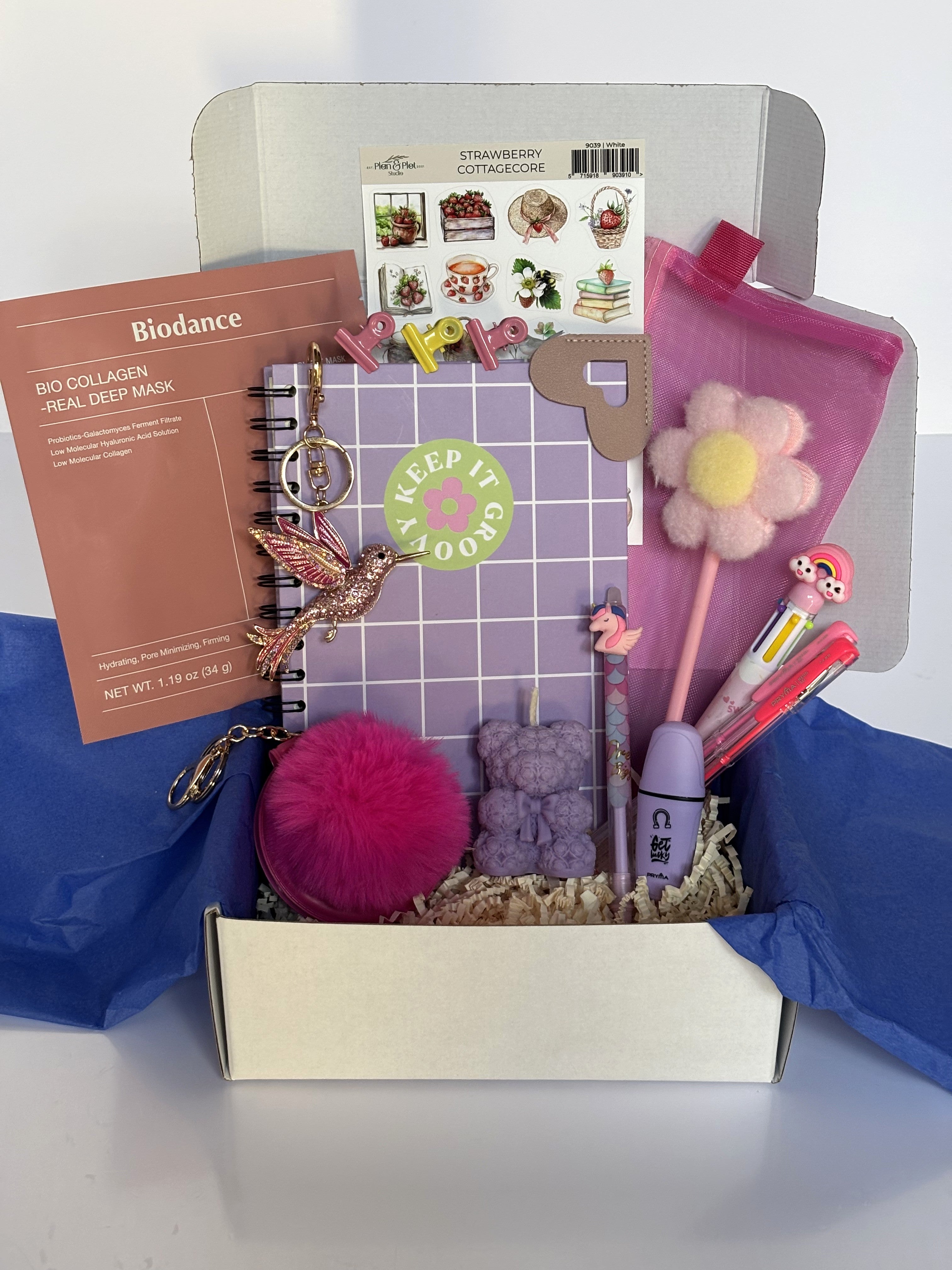 Cofanetto regalo Positive Energy C.Moon da 64.90€ in variante lilla, con quaderno a scacchi, candela a orsetto lilla, maschera Biodance rosa e portachiavi specchietto fucsia.
